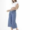 Mujer vistiendo pantalón de mezclilla azul de corte ancho hasta media pierna, combinado con blusa blanca, ideal para un estilo casual y moderno