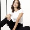 Mujer con jean negro elastizado, combinándolo con un top blanco en un look relajado.