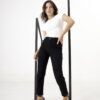 Mujer con jean negro de tiro alto y tela elastizada, posando con un outfit minimalista.