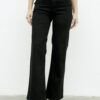 Primer plano del jean flare negro con faja moldeadora y botones metálicos que realzan la silueta.