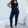 Primer plano del detalle del botón y faja ancha de jean chupin azul oscuro localizado.