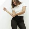 Primer plano de mujer luciendo jean clásico Oxford negro localizado con camiseta blanca, fondo claro.