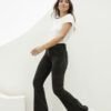 Modelo caminando con jean Oxford nevado negro y botines blancos sobre fondo claro.