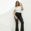 Modelo de pie luciendo jean Oxford nevado negro y remera blanca en fondo minimalista.