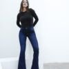 Mujer de pie usando jean Oxford azul con camiseta negra en ambiente minimalista