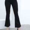 Vista frontal de mujer usando jean clásico Oxford negro con bota acampanada y tacones, sobre fondo blanco minimalista