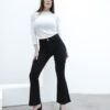 Modelo de pie con pose lateral mostrando el jean Oxford negro y blusa blanca ajustada