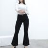 Vista frontal de mujer modelando jean Oxford negro con blusa blanca, brazos cruzados, en ambiente blanco.