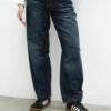 Primer plano de jean baggy azul localizado oversize con costuras marcadas y calzado deportivo.