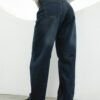 Modelo usando jean baggy azul localizado con efecto gastado, en pose urbana y moderna.
