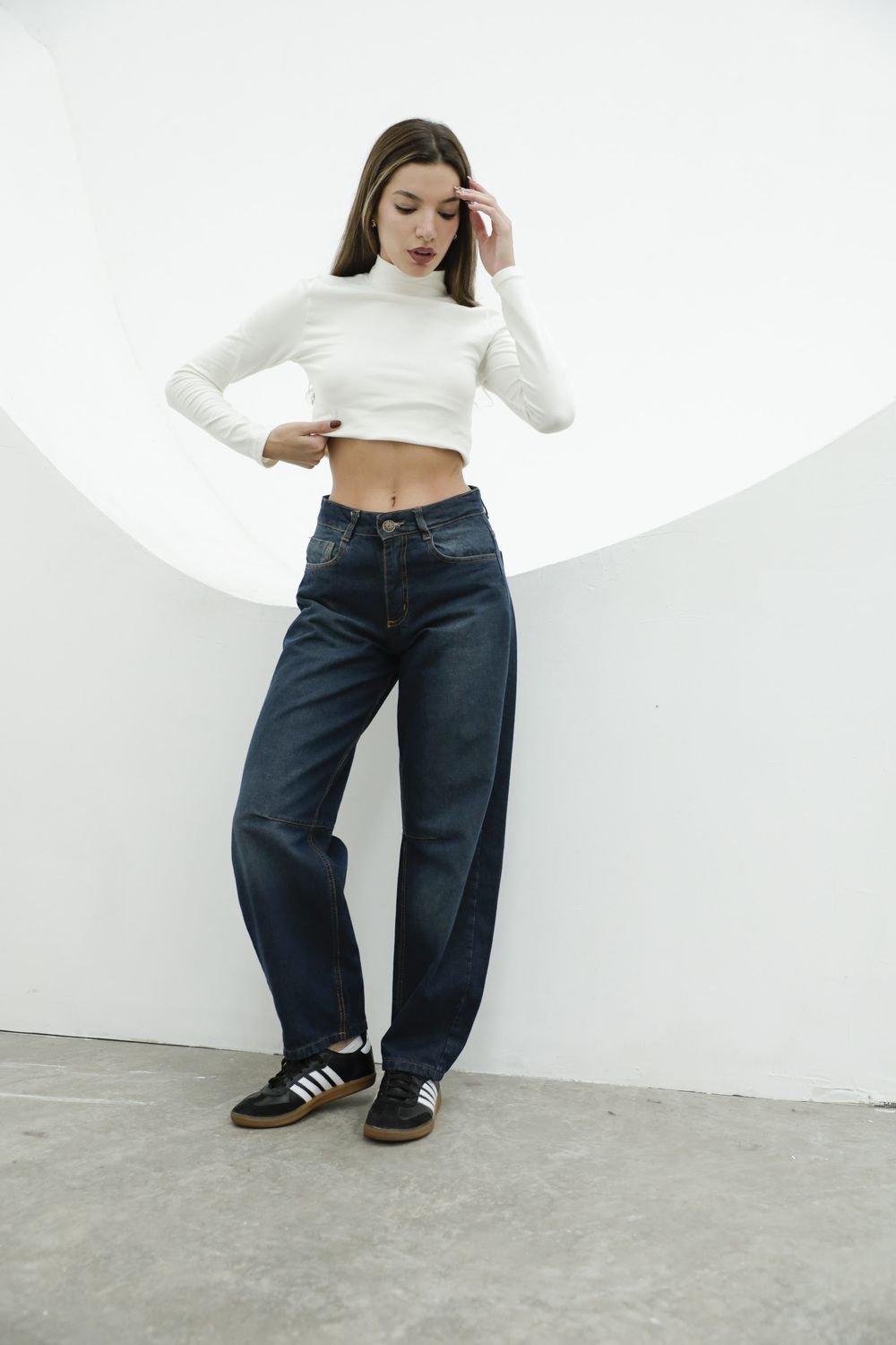 Mujer con look urbano moderno luciendo jean baggy azul localizado y zapatillas blancas.
