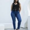 Mujer de frente luciendo jean chupín azul clásico, corte ajustado con blusa sin mangas negra.