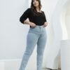 Modelo de frente usando jean recto celeste nevado con blusa negra, posando con confianza y elegancia casual.