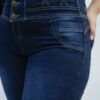 Close-up de faja y costuras decorativas del jean azul oscuro localizado con tres botones y diseño en “X”.