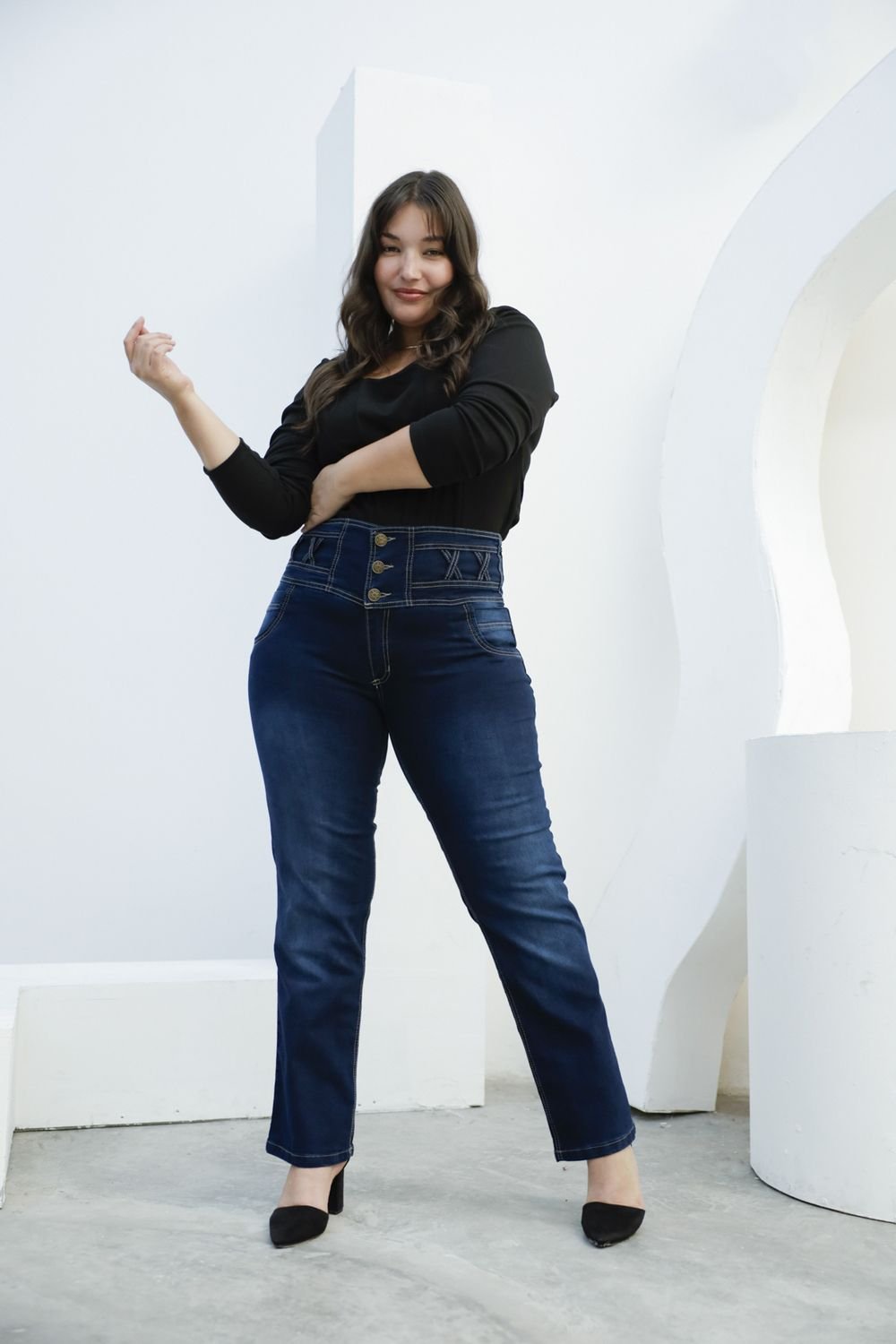 Mujer luciendo jean azul oscuro con faja, posando con actitud y expresión segura.