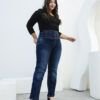 Modelo caminando con jean recto azul oscuro de cintura alta con faja marcada y acabado localizado.