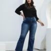 Modelo usando jean wide leg azul localizado con mano en la cadera y blusa negra, en pose casual.