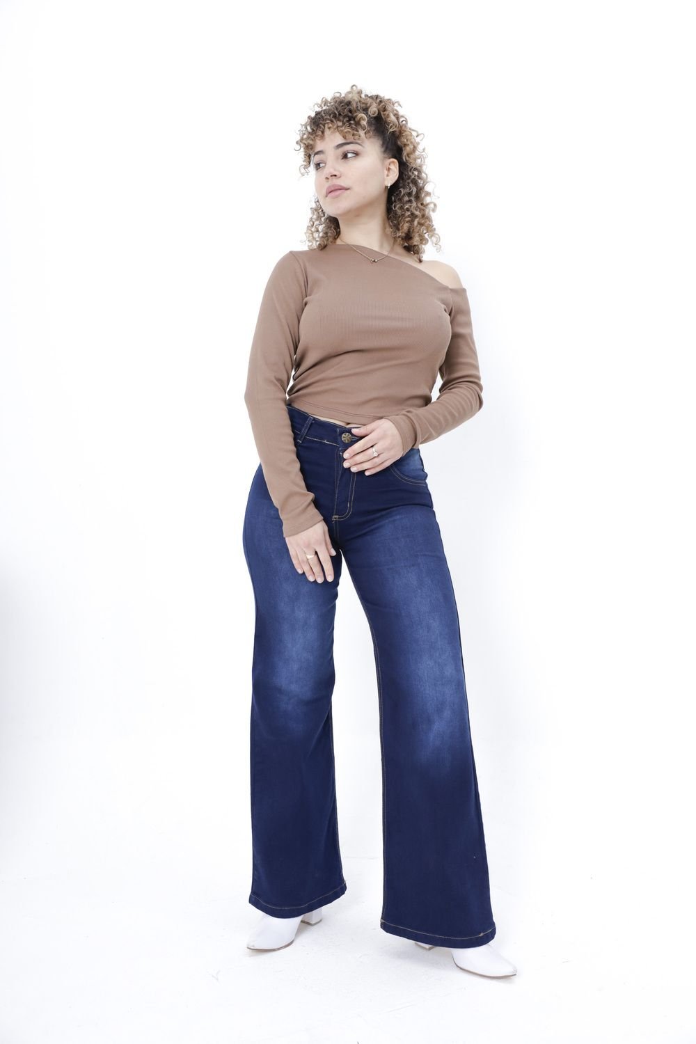Mujer con jean azul oscuro wide leg posando de frente con mano en la cintura, fondo blanco.