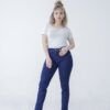 Mujer joven luciendo jean chupín clásico azul oscuro en look casual con remera clara y botas con taco.