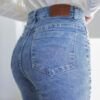 Detalle trasero de jean wide leg celeste con etiqueta marrón de cuero y costura prolija.