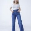 Mujer luciendo jean faja wide leg azul denim localizado de tiro alto y corte amplio, combinándolo con remera gris y botines blancos.