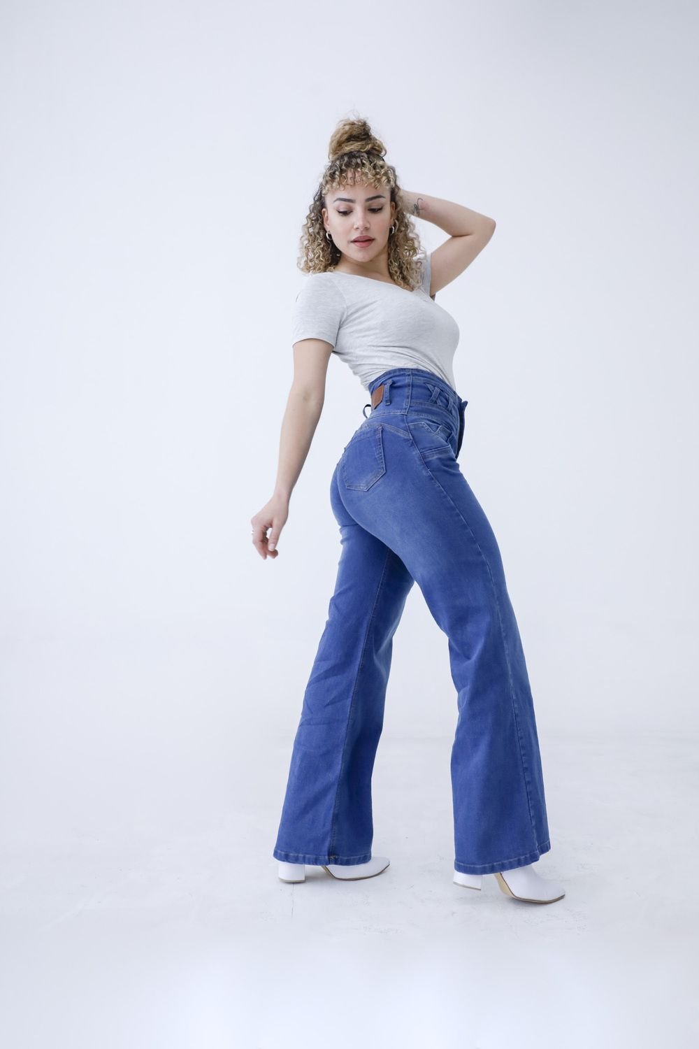 Modelo posando de perfil con jean faja wide leg azul denim localizado, mostrando la fluidez del corte y el ajuste en cintura.