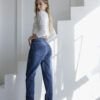 Vista trasera de jeans mom fit azul, con remera blanca ajustada y botas blancas, en espacio con luz natural.