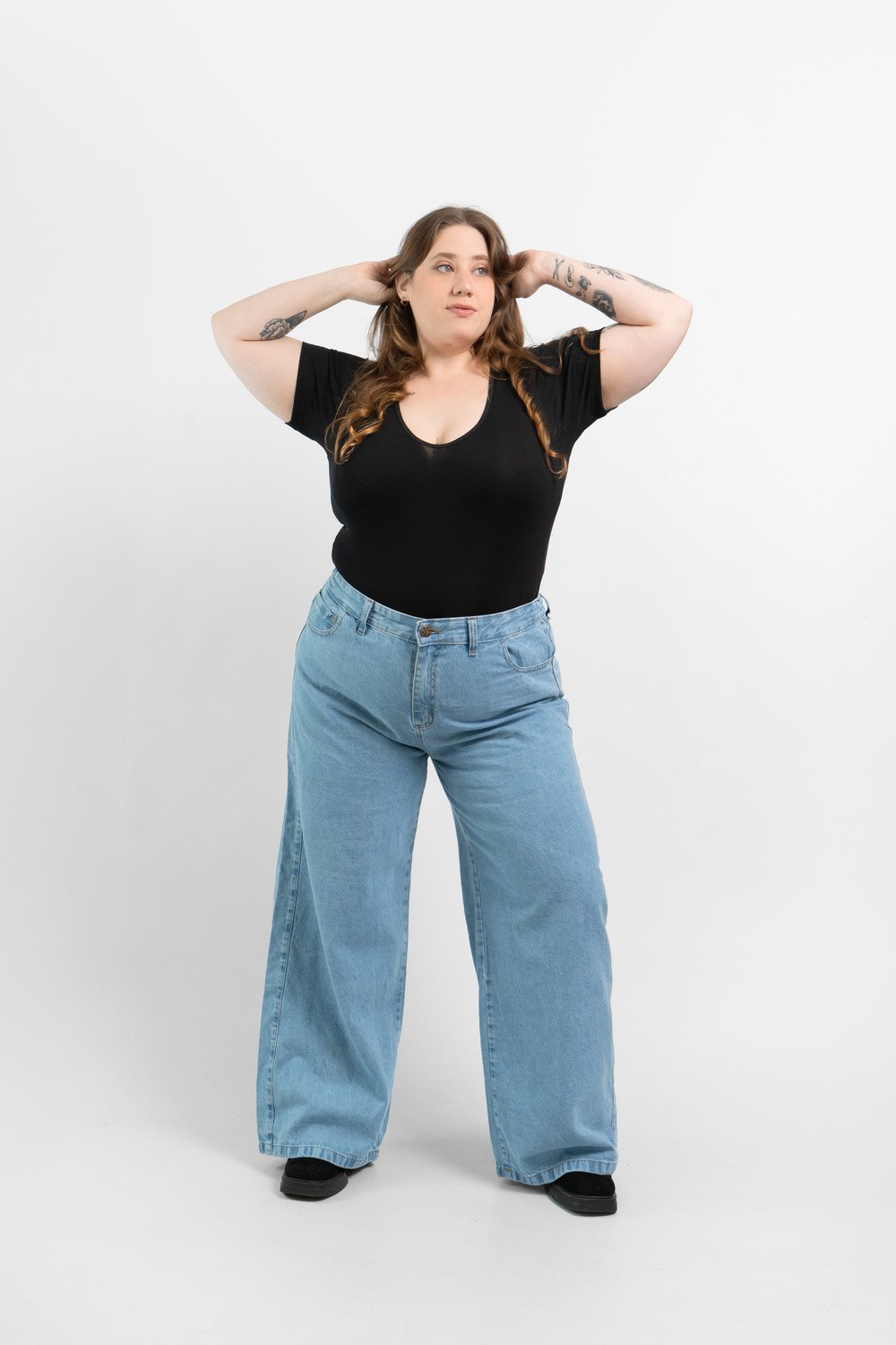 Modelo con los brazos levantados usando un jean Maxi Wide Leg Plus Size azul nevado